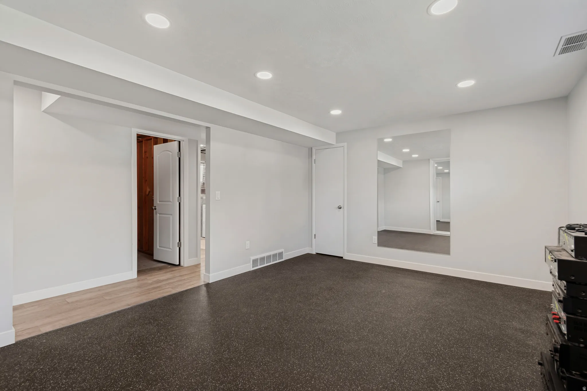 Recessed lighting, light gray walls, white trim, wood-finish flooring, and a large wall-mounted mirror