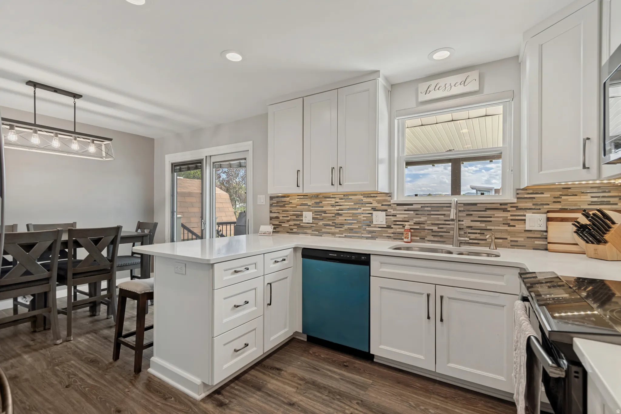 White shaker-style cabinetry, white countertops, mosaic tile backsplash, wood-finish flooring, and a stainless steel sink with a gooseneck faucet