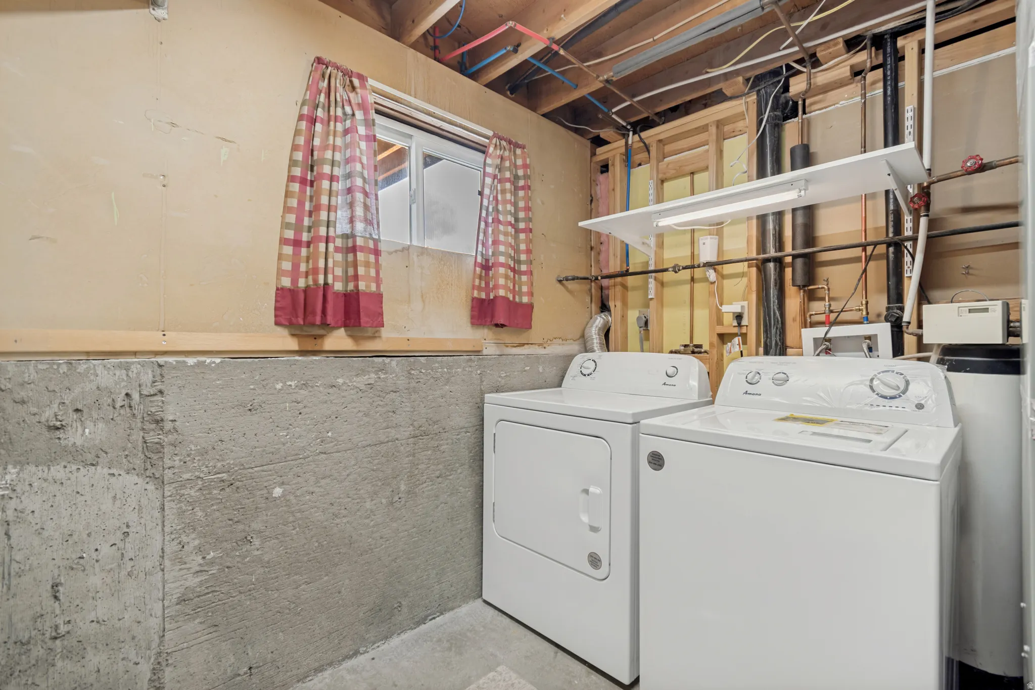 Utility area featuring concrete walls, a window, exposed ceiling joists, and a water softener system
