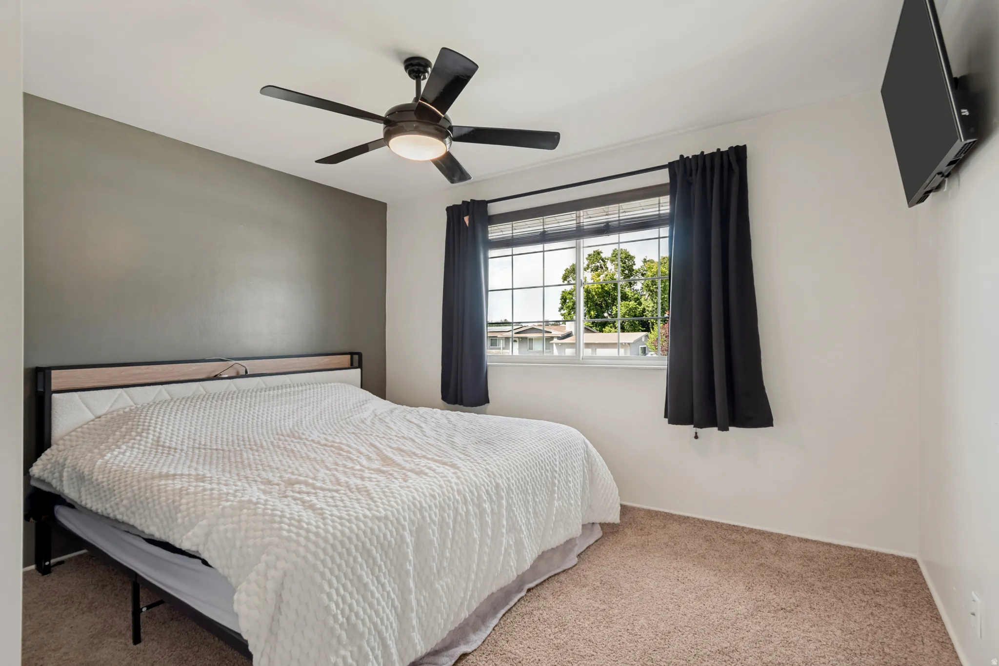 Built-in ceiling fan with light fixture, window with grid panes, wall-to-wall carpeting, and accent wall
