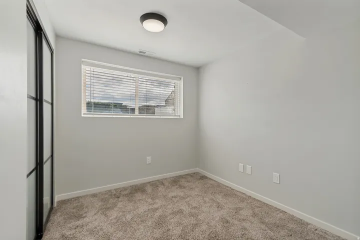 Neutral wall color, window with blinds, flush-mount ceiling light, and carpeted flooring