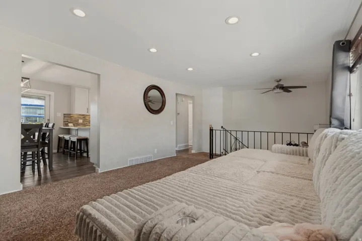 Recessed lighting, ceiling fan, carpet flooring, open archway, and iron railing