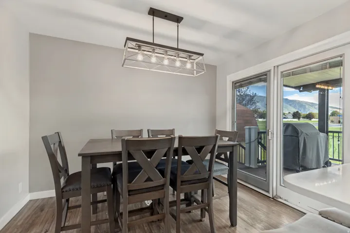 Wood-finish flooring with a modern linear chandelier, light gray walls, and white trim
