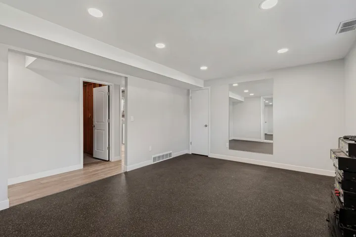 Recessed lighting, light gray walls, white trim, wood-finish flooring, and a large wall-mounted mirror