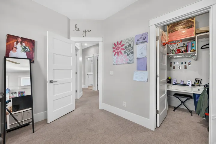 Neutral wall tones, carpet flooring, a built-in closet desk, and white trim work