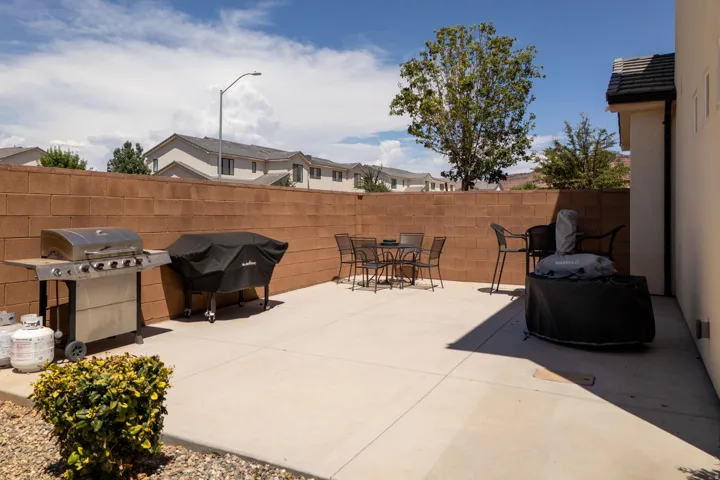 Paved patio area featuring a block privacy wall and exterior wall