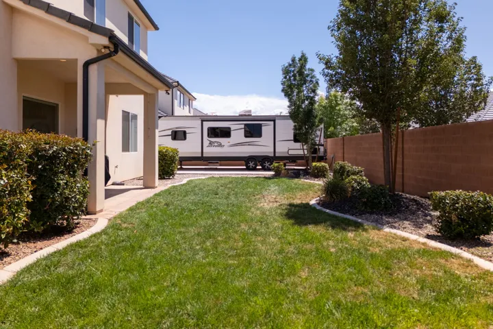 Expansive backyard featuring a manicured lawn, established shrubs, and mature trees