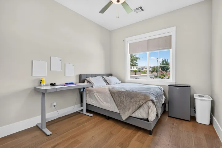 Wood-finish flooring, white trim, recessed lighting, ceiling fan, and large window