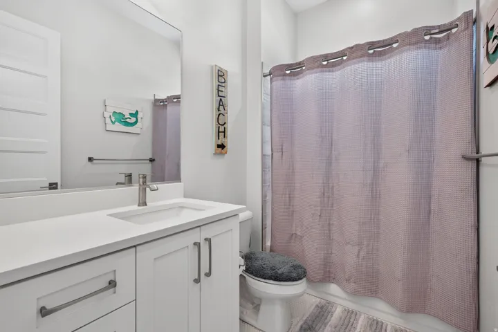 White vanity with brushed nickel hardware, integrated rectangular sink, and a framed mirror