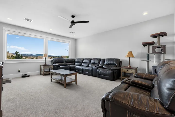 Expansive windows, recessed lighting, ceiling fan, neutral wall tones, and light-toned carpeting