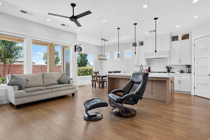 Open-concept living area with wood-finish flooring, recessed lighting, and a contemporary ceiling fan