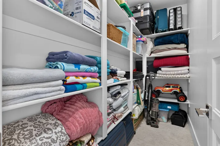 Built-in shelving with multiple storage levels, light neutral wall paint, and light-colored flooring