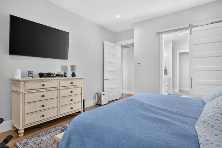 Recessed ceiling lighting, wood-finish flooring, white solid core doors, and a white barn door