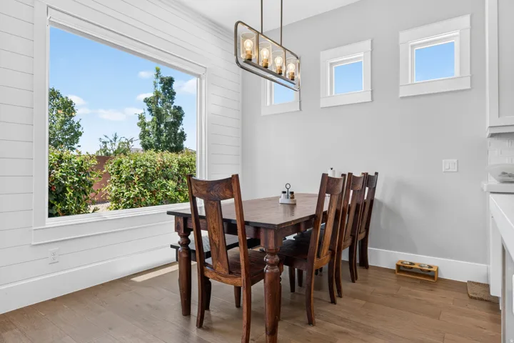 Wood-finish flooring with white baseboards, shiplap accent wall, and a linear chandelier