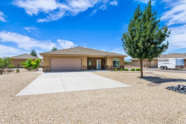 Single-story residence featuring a two-car garage, stone and stucco exterior, arched window, and a concrete driveway