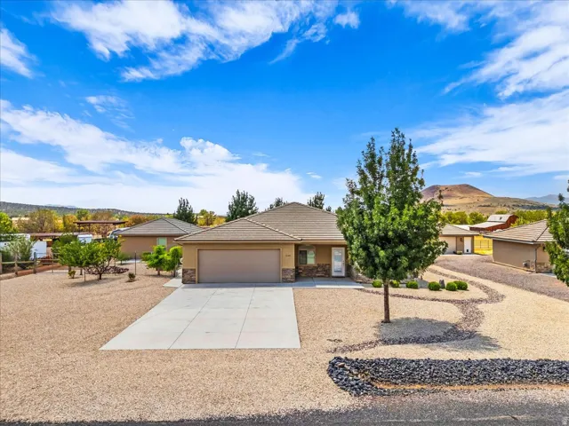 Single-story residence featuring a two-car garage, stone façade accents, and a paved driveway