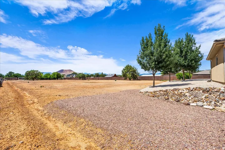 Expansive undeveloped land featuring a gravel rock bed, established trees, and surrounding fencing