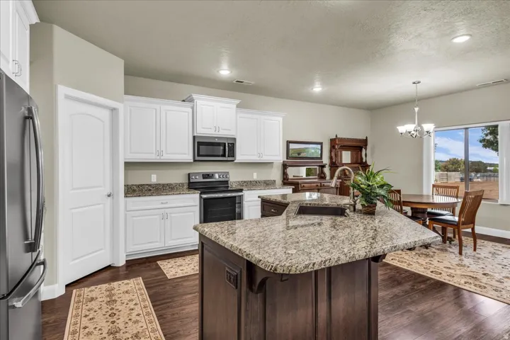 Kitchen featuring wood-finish flooring, white cabinetry, granite countertops, and stainless steel appliances
