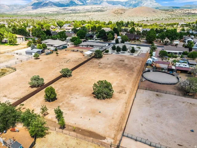 Expansive undeveloped land with sparse trees, perimeter fencing, and a round pen