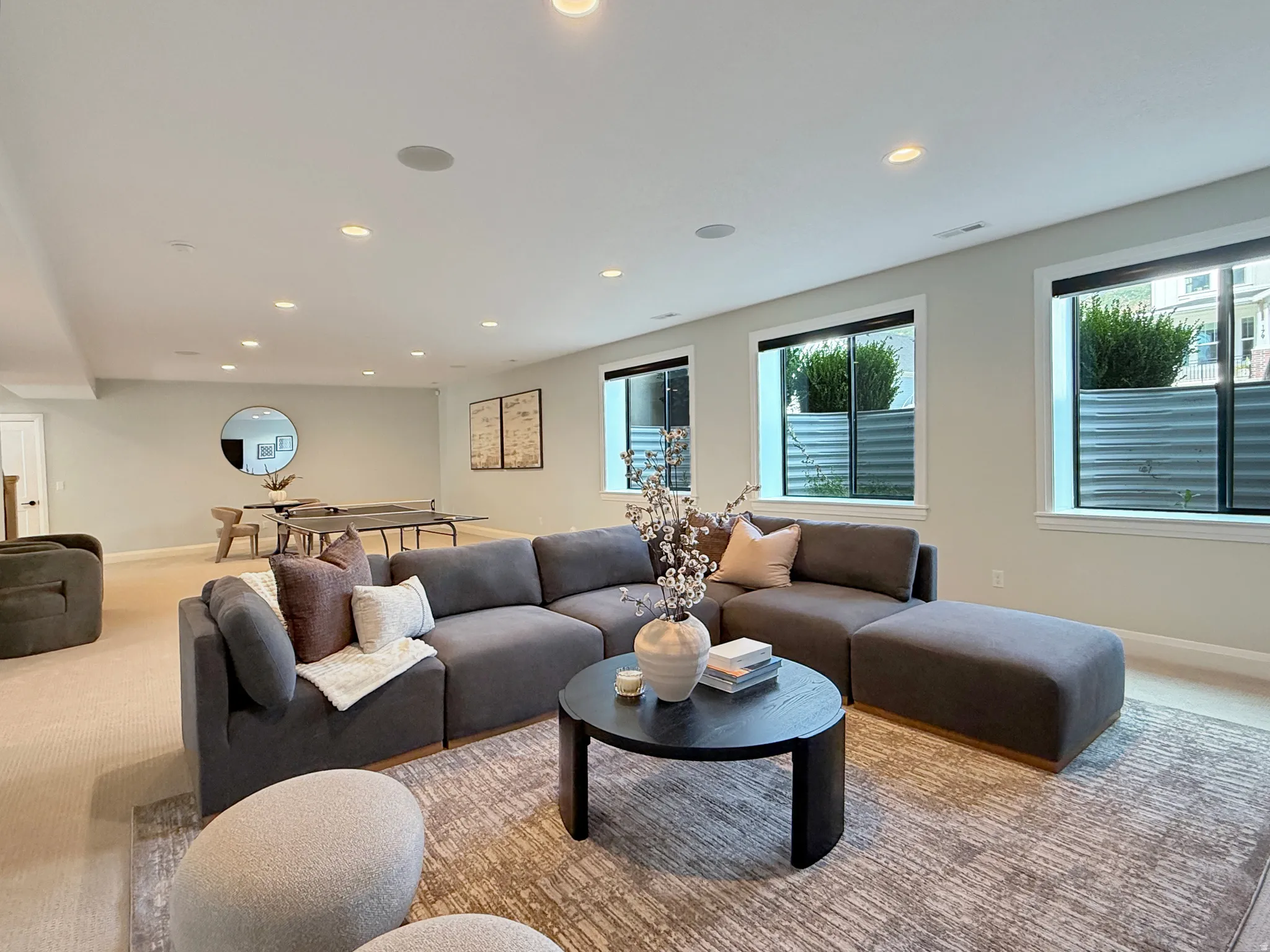 Recessed lighting throughout a spacious room with light-toned walls and multiple windows