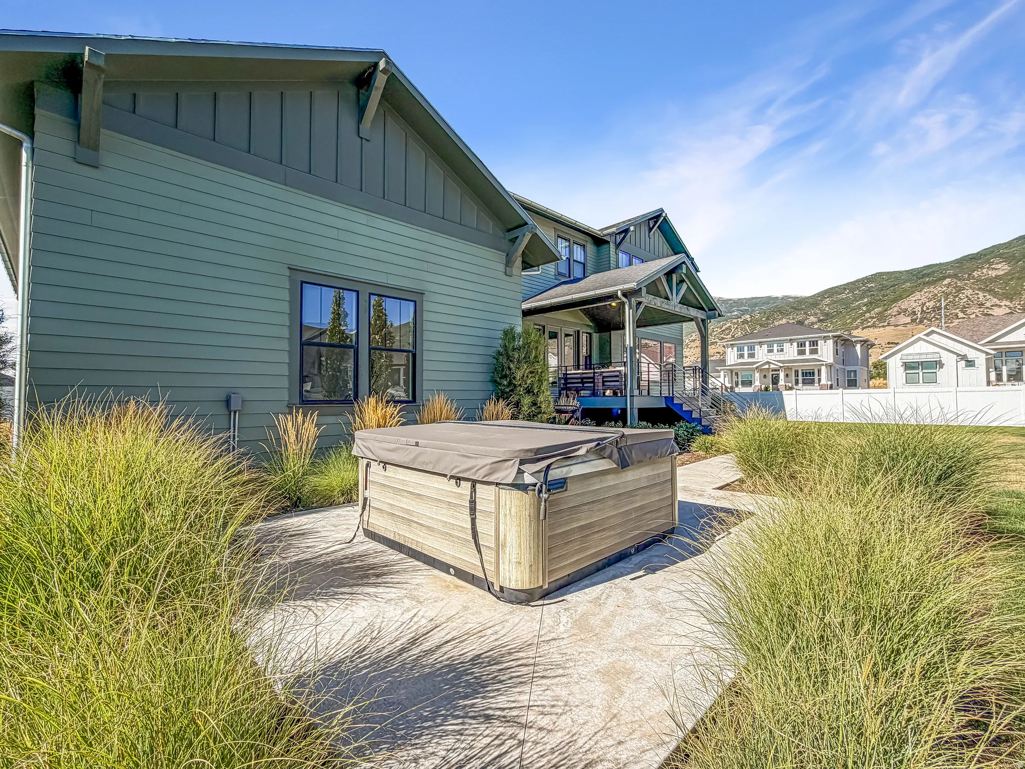 Exterior featuring board-and-batten and horizontal siding, covered porch with columns, and a built-in hot tub on a concrete patio