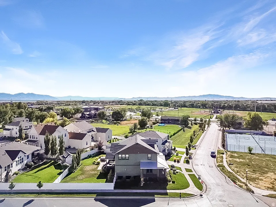 Aerial perspective showcasing a residential street, a two-story property with a fenced yard, and a distant mountain range