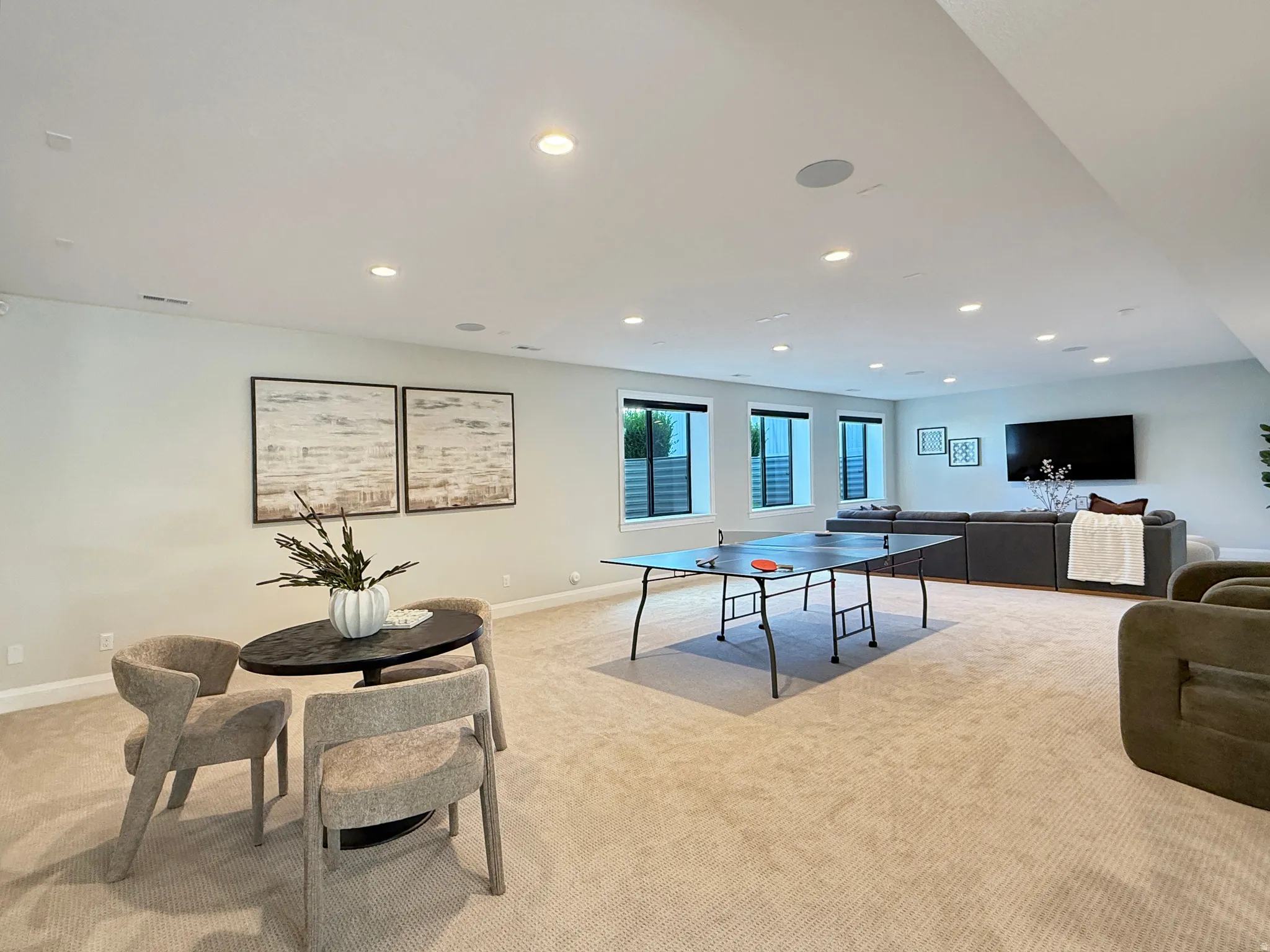 Recessed lighting throughout a spacious room with light-colored carpeting