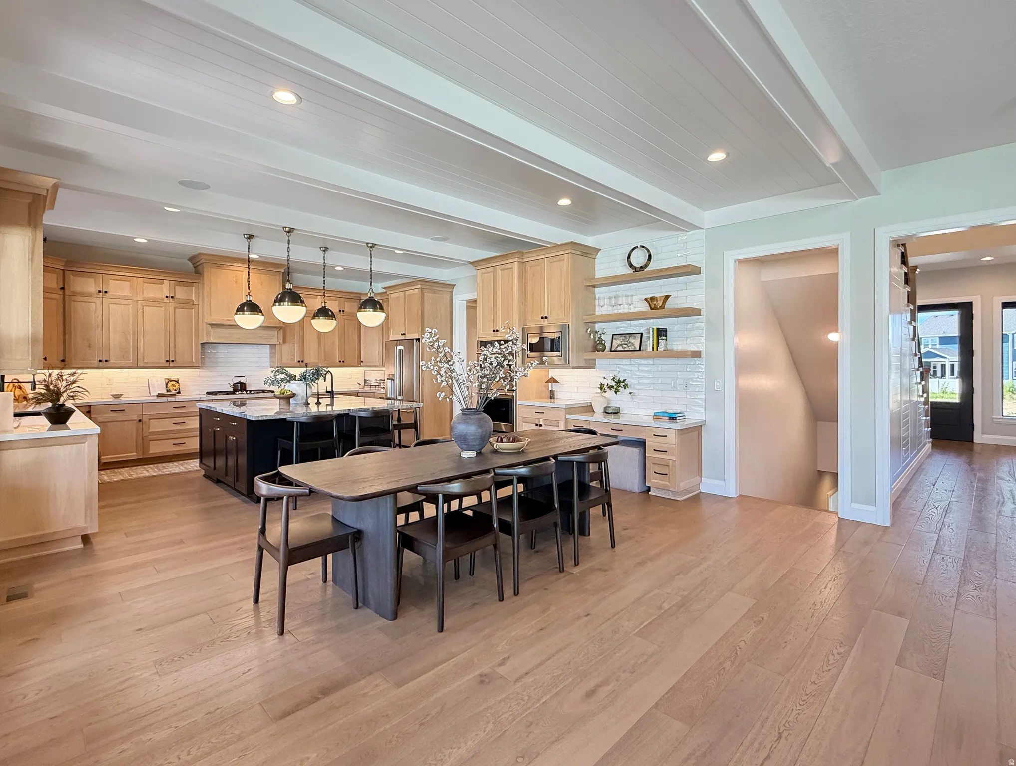 Open concept kitchen with wood-finish flooring, light wood cabinetry, a dark kitchen island, and a dining table