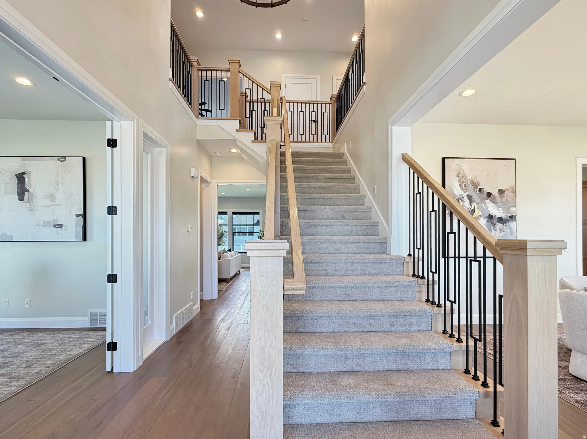 Two-story foyer with wood-finish flooring, carpeted staircase, and contemporary railing