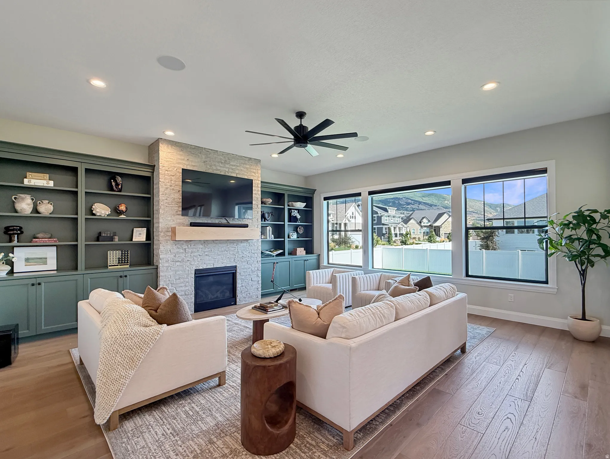 Spacious room featuring extensive built-in cabinetry, an electric fireplace with a stacked stone facade, a wood-finish mantel, and large windows with mountain scenery