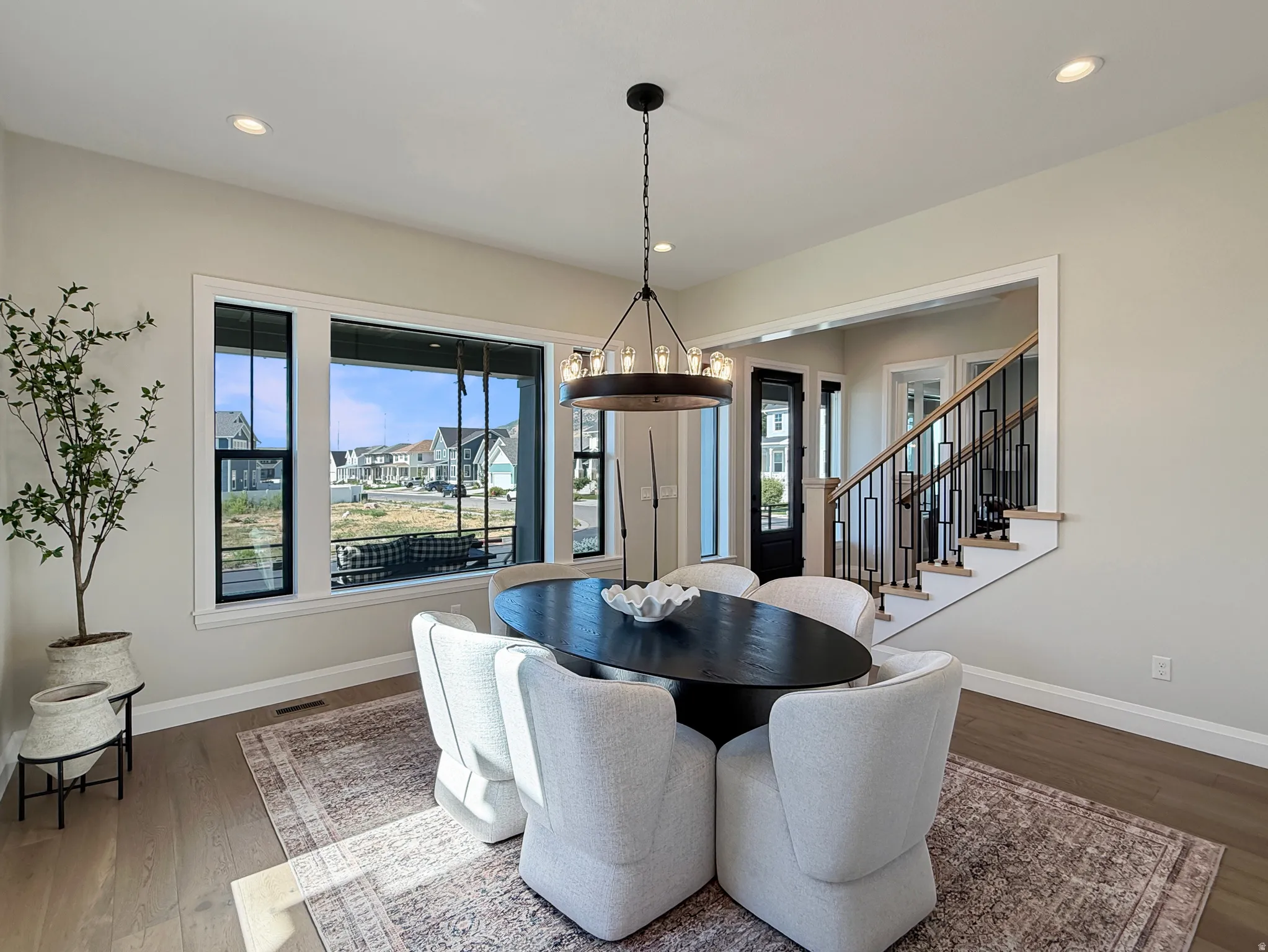 Wood-finish flooring, recessed lighting, and a modern chandelier illuminate this space