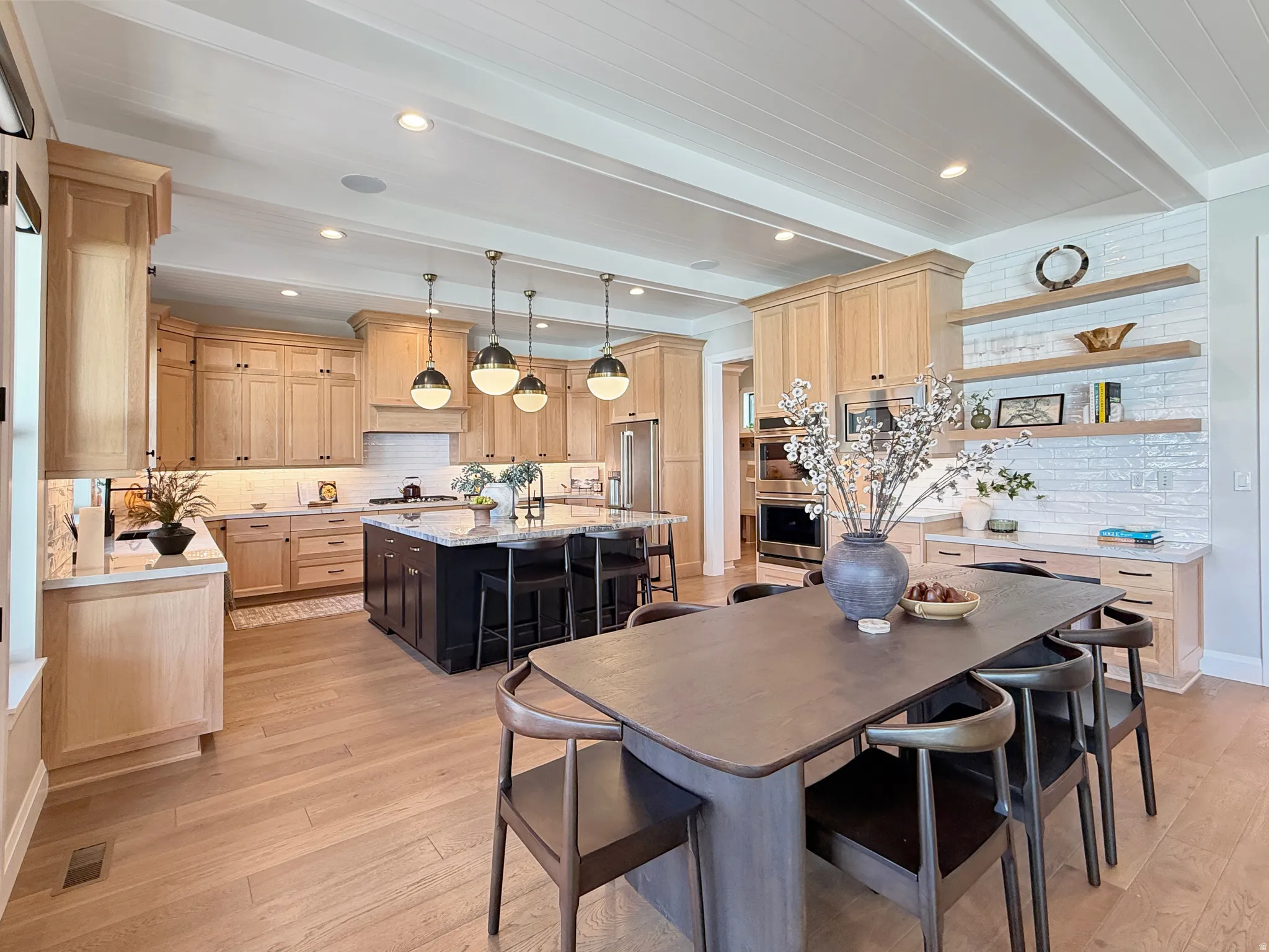 Open-concept kitchen with light wood-finish cabinetry, a dark-toned island, and light wood-finish flooring