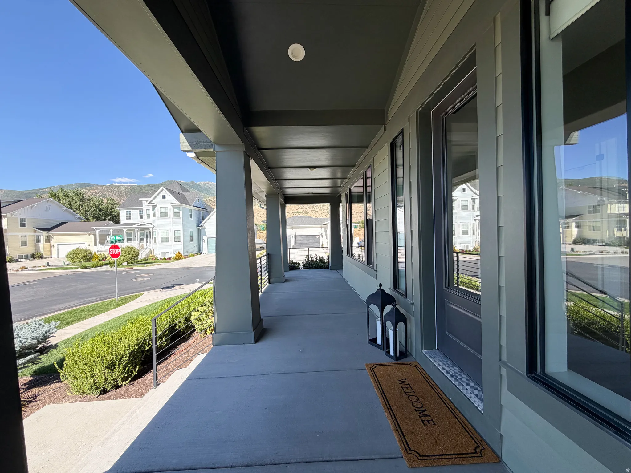 Expansive covered porch featuring a solid front door, multiple windows, and mountain scenery
