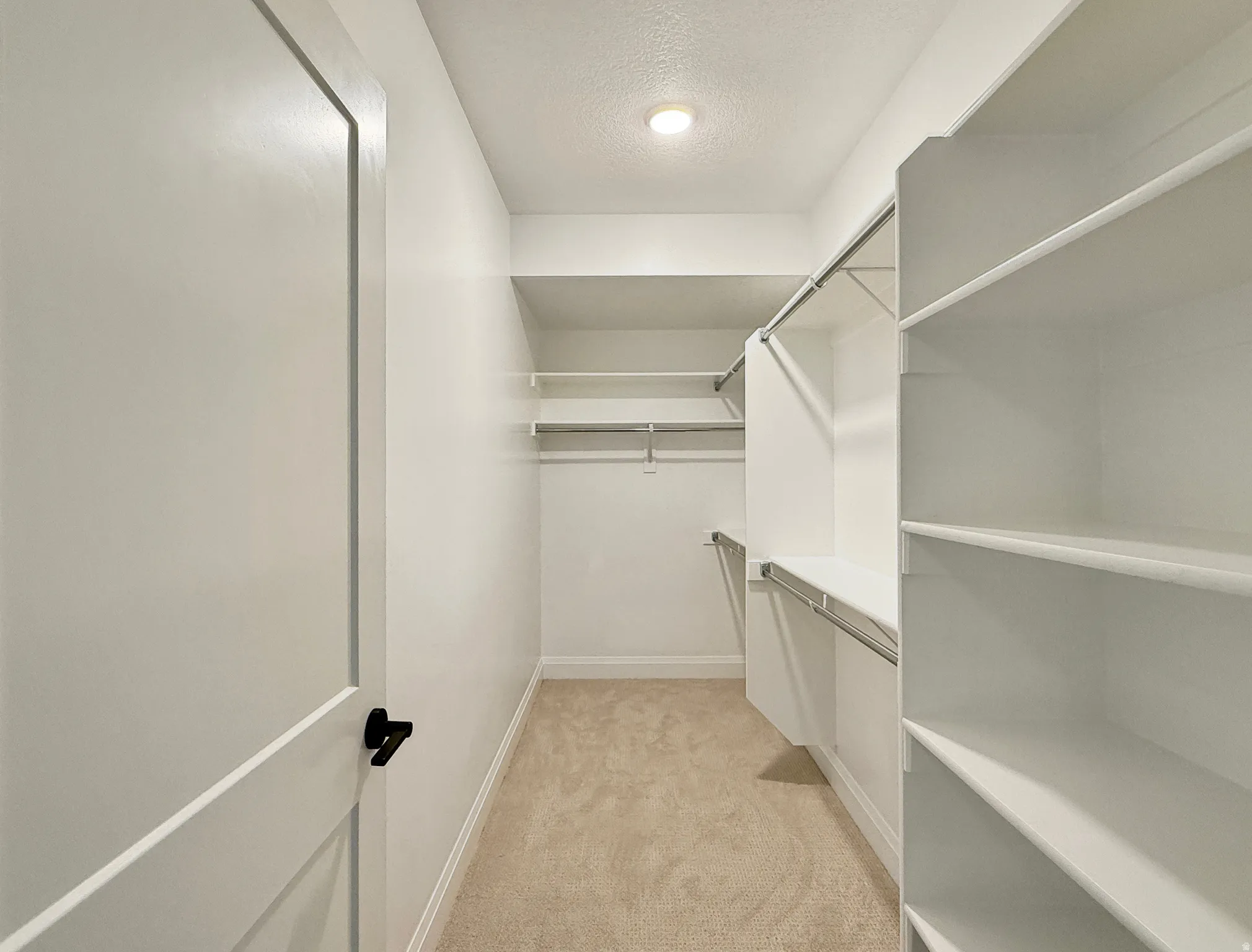 Walk-in closet featuring built-in shelving, chrome hanging rods, and recessed lighting