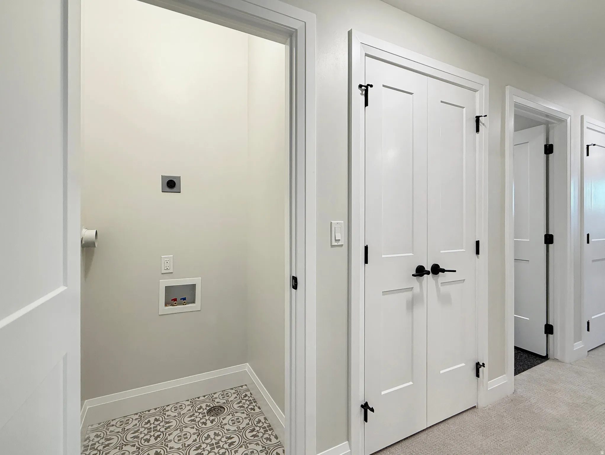 Dedicated laundry nook with patterned floor tiles, white walls, and utility hookups