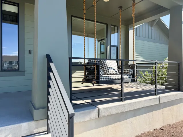 Covered porch with concrete flooring, modern black metal railing, and vertical window