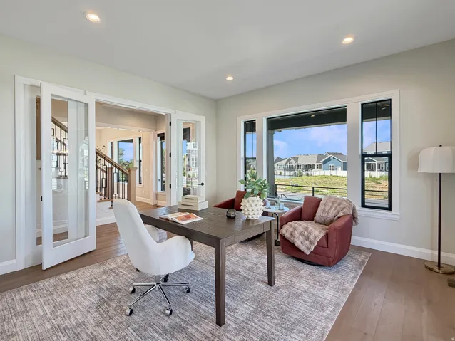French doors with glass panels, recessed ceiling lighting, large windows with dark trim, light wood-finish flooring, and neutral wall tones
