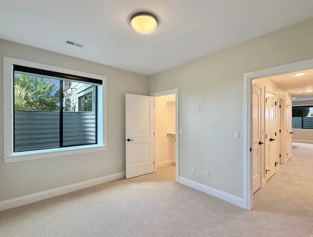 Neutral carpet flooring, recessed ceiling light, white trim, flat panel interior doors, and a window with blinds