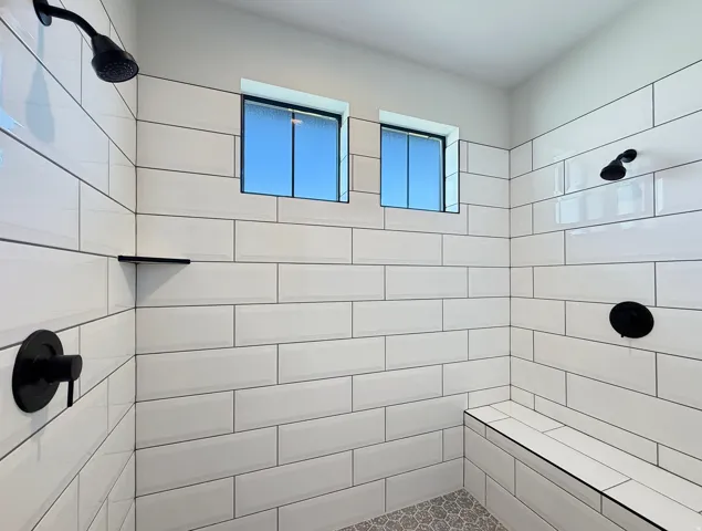 Shower with subway tile, built-in bench, two shower heads, and matte black fixtures