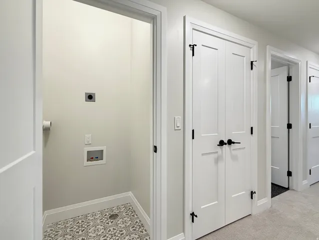 Dedicated laundry nook with patterned floor tiles, white walls, and utility hookups