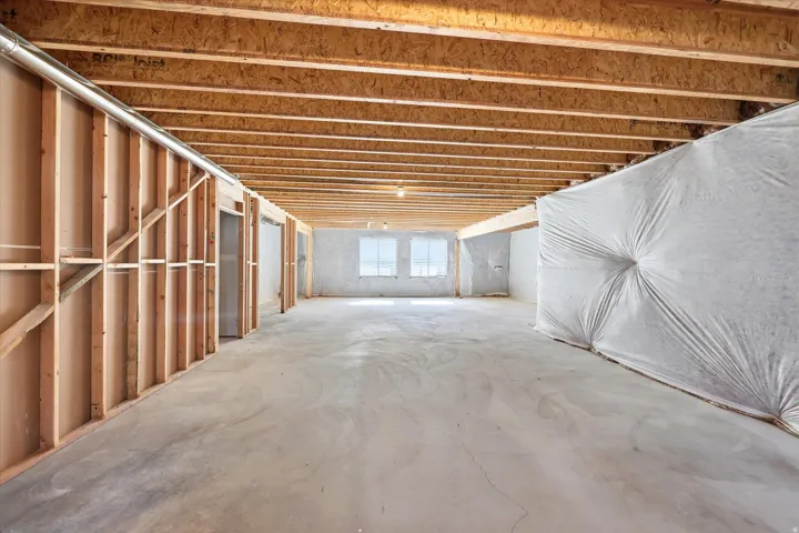 Unfinished lower level with exposed ceiling joists, concrete flooring, and framed interior walls