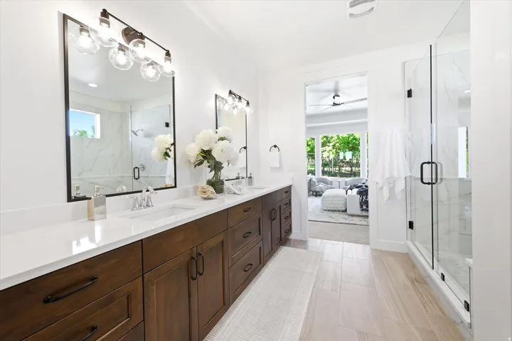 Dual vanity with wood-finish cabinetry, white countertop, and rectangular undermount sinks