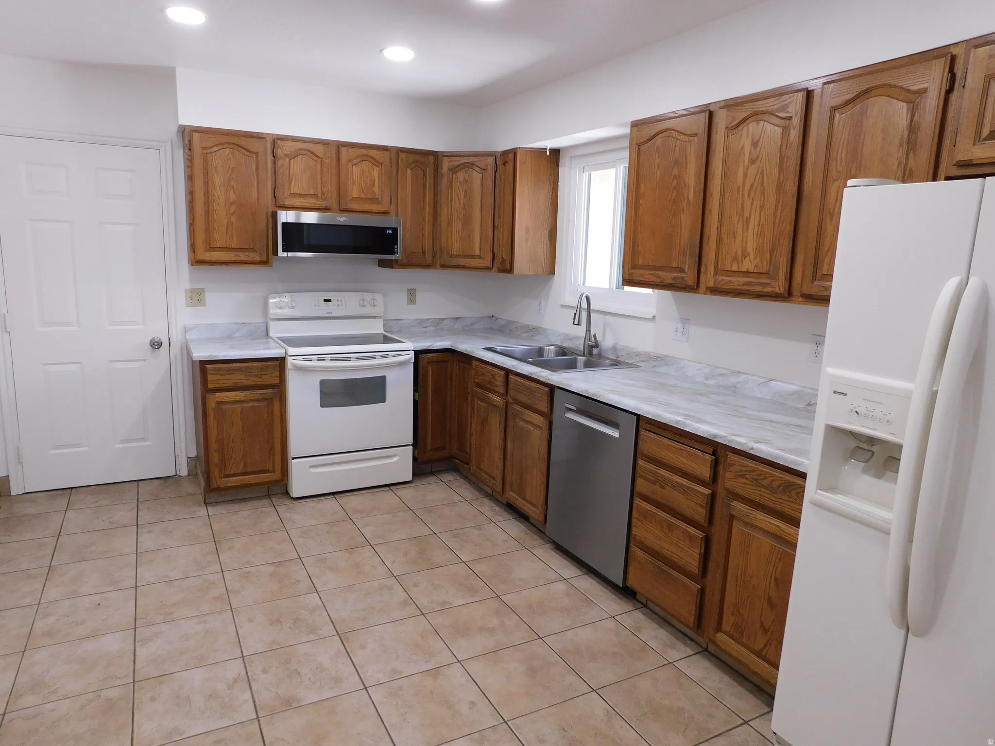 U-shaped kitchen with wood cabinetry, light-toned countertops, and tile flooring