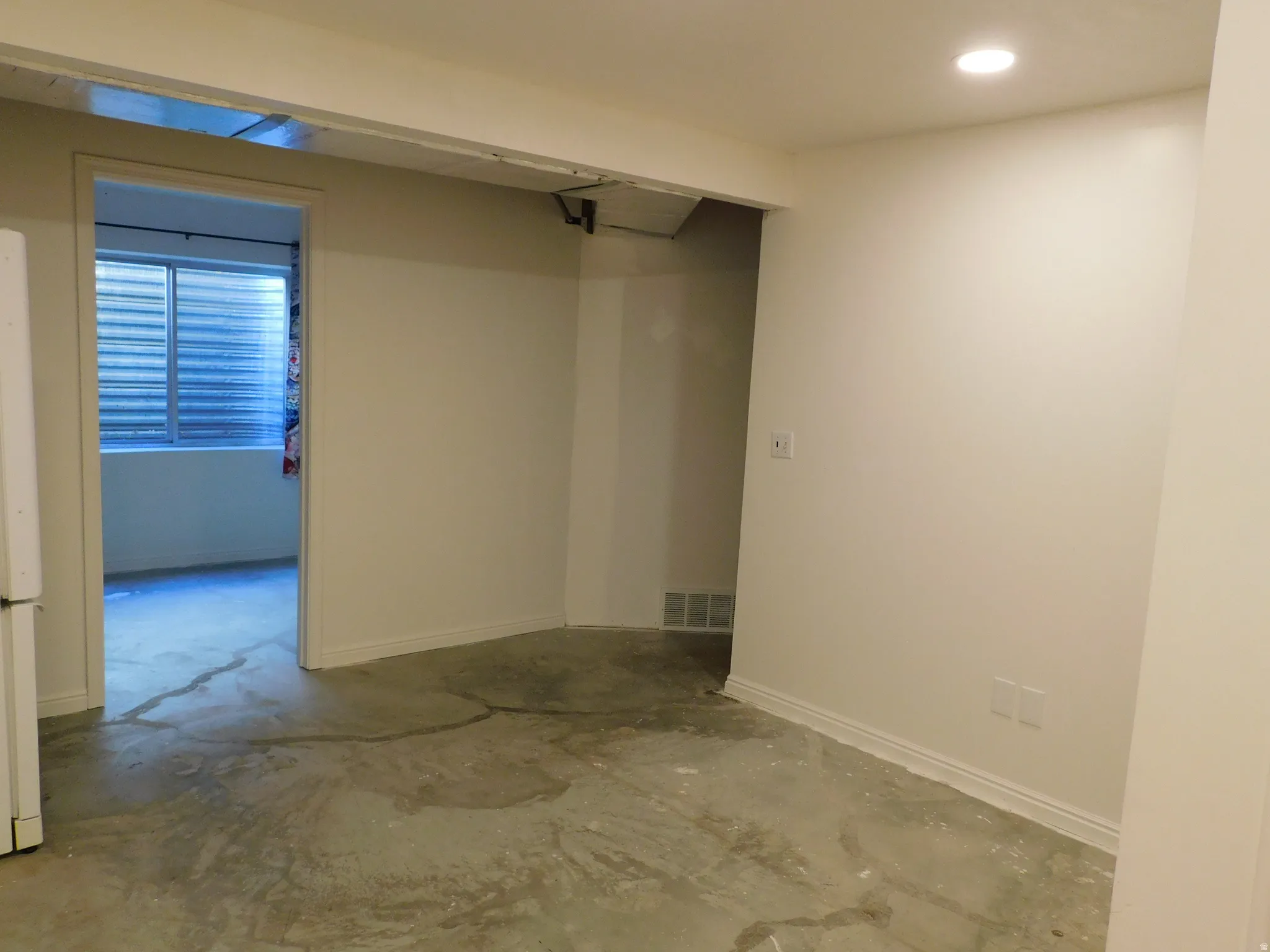 Interior space with a recessed ceiling light, white painted walls, and concrete flooring