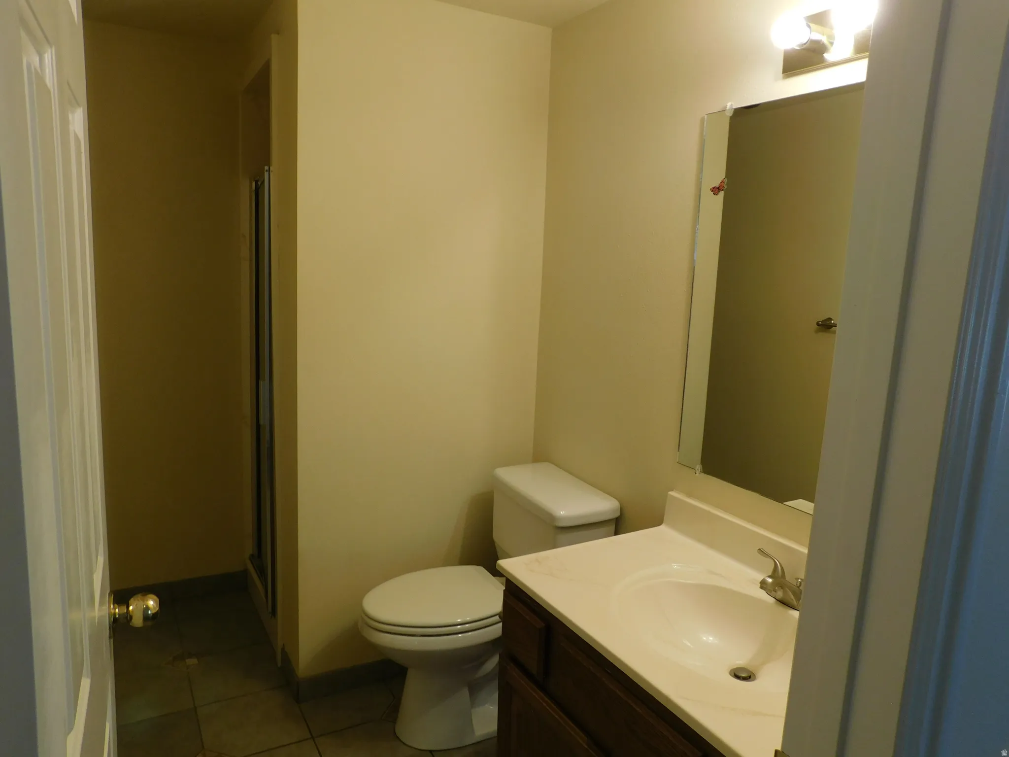 Bathroom featuring a vanity with an integrated sink, a wall-mounted mirror, a toilet, and a shower enclosure