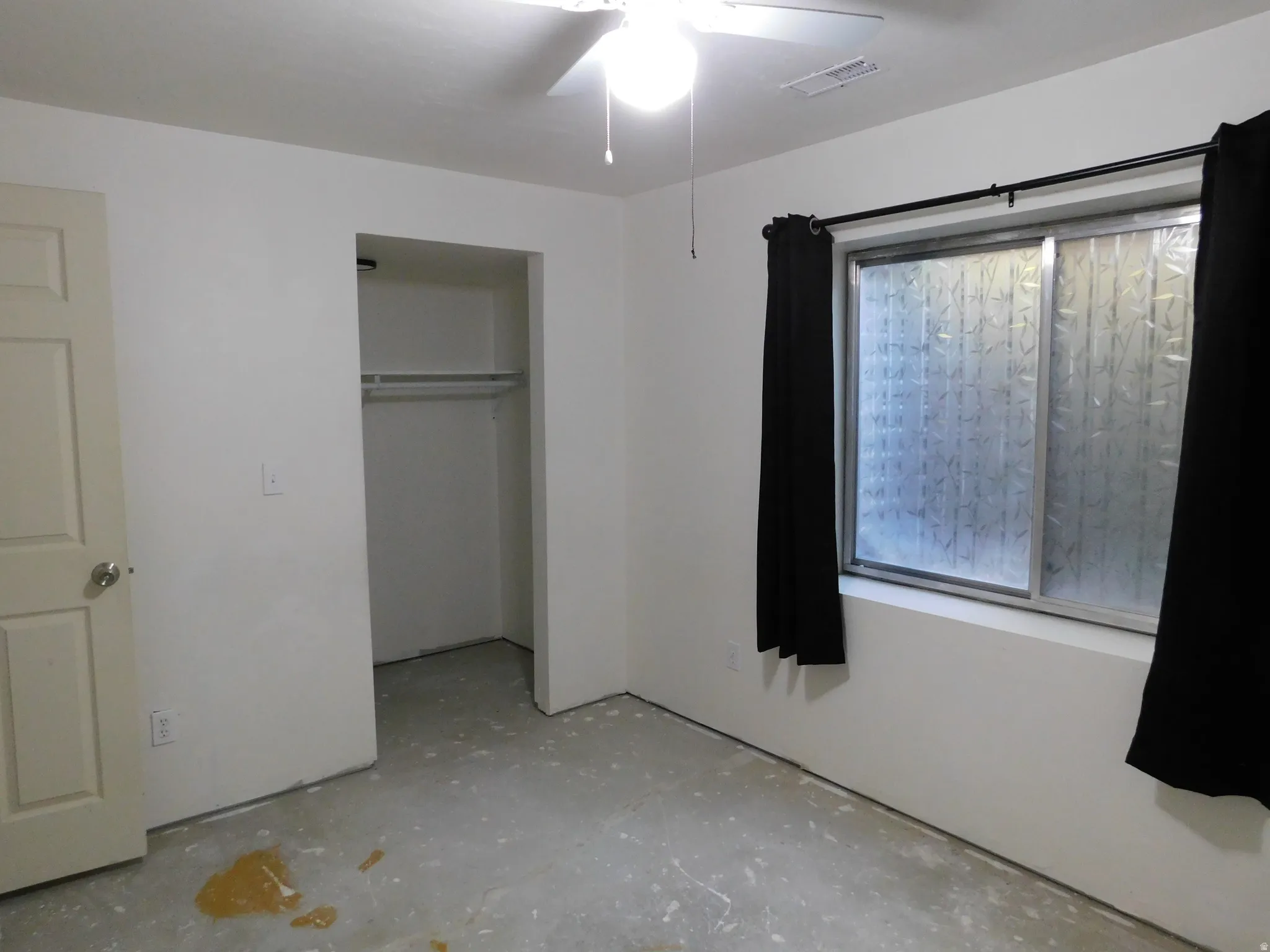 Recessed closet with a single hanging rod, ceiling fan with illumination, and a window