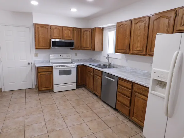 U-shaped kitchen with wood cabinetry, light-toned countertops, and tile flooring