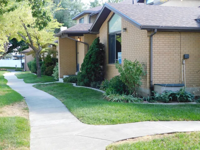 Brick exterior with a peaked roofline, a large picture window, and mature landscaping