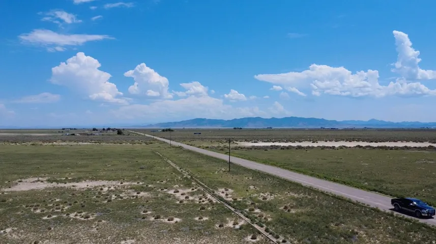 Expansive open terrain with a distinct paved road traversing the property, complemented by distant mountain ranges
