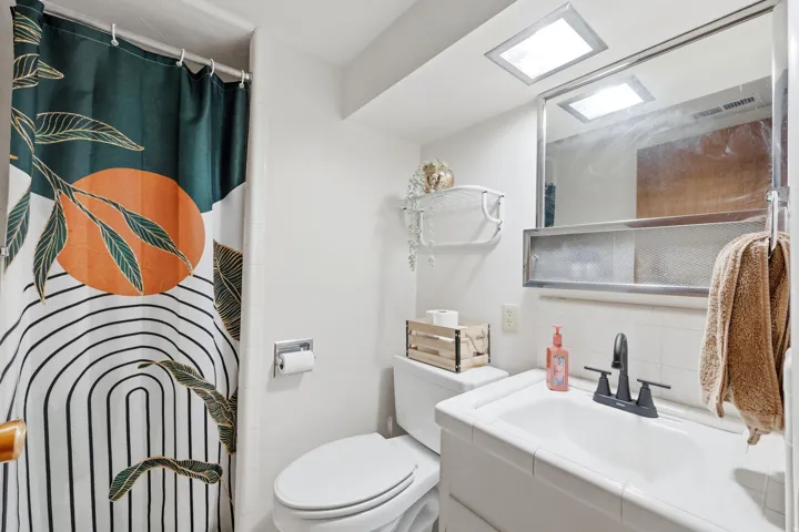 Full bathroom featuring white tile walls, a white vanity with an integrated sink, and a matte black faucet
